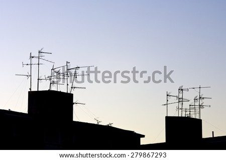 Silhouettes of TV antennas on a roof.
