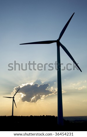 two windmills against cloudy sky at sunset