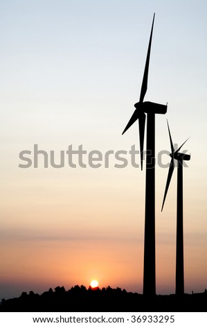 two windmills at sunrise with sun