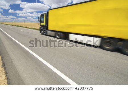 circulating yellow truck speeding along a straight road