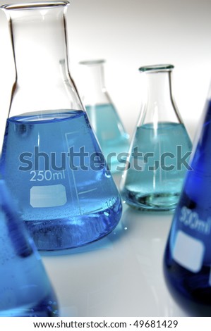 conical flasks with blue and green liquid in a laboratory