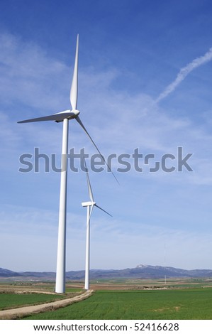 two windmills in a field with blue sky