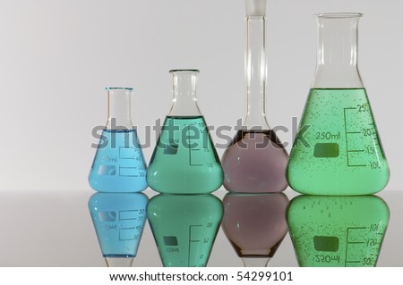 four chemical laboratory flasks with colored liquid