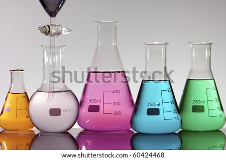 forefront of a laboratory flasks containing brightly colored liquid