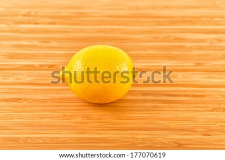 Yellow lemon sit on a worn butcher block cutting board