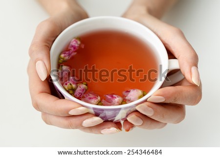 hands that hold a cup of tea from the flowers of roses