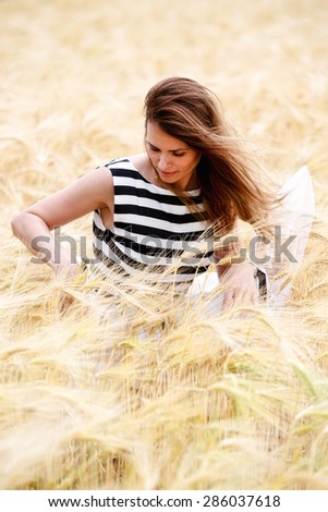 gorgeous girl walking in the field of long grass and dragging her hand touching the dry grass while laughing and smiling, carefree healthy lifestyle