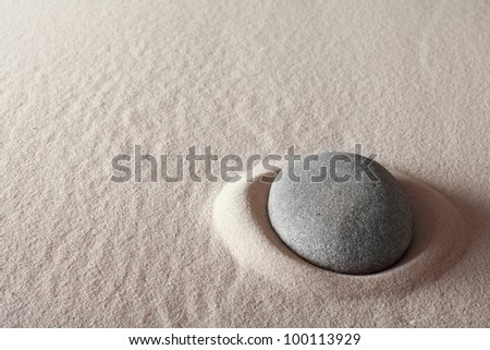 zen meditation stone relaxation or concentration point to focus and to meditate round grey rock in sand simplicity and purity spa background