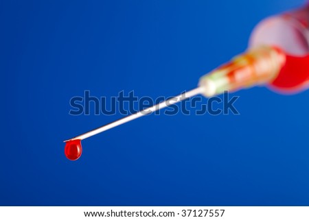 syringe needle with droplet of blood on blue background