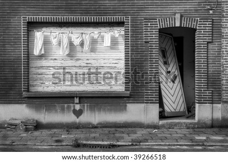 laundry in front of the window of an abandoned house with a broken door