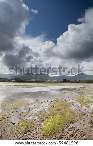 White clouds in blue sky over Irish hills and estuary at Dingle peninsula Kerry district Ireland