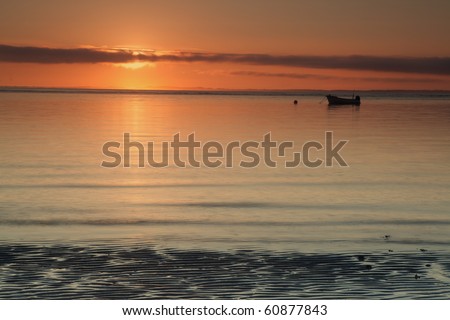 glowing sunrise over Irish sea seascape with lonely boat and calm tranquil water surface