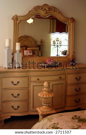 romantic bedroom with bed reflected in mirror on dresser