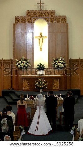 wedding party standing at altar in catholic church during wedding ceremony