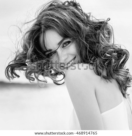 Black and white portrait of a young beautiful woman. Woman in Black & White. Black and white portrait of smile woman. Close-up. Black white photography.  Autumn portrait on the beach.