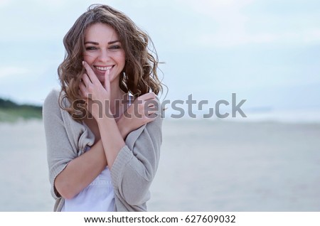 Woman Portrait on the beach. Happy beautiful curly-haired girl close-up, the wind fluttering hair. Spring portrait on the beach. Young pretty girl. Young smiling woman outdoors portrait. Close. ocean.