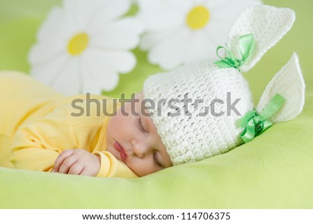 sleeping baby in funny rabbit hat on green background