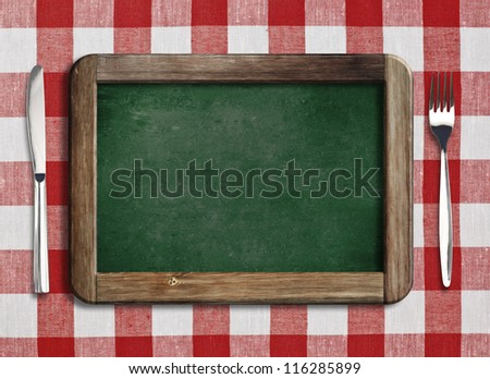 Menu blackboard lying on table with knife and fork