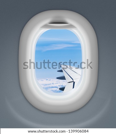 airplane window with wing and cloudy sky behind