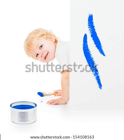 Baby boy with paint brush on all fours behind painted white wall