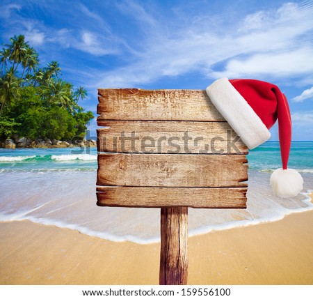Christmas On Beach. Wooden Signboard With Santa\'S Hat.