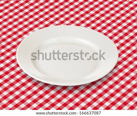 white plate over red checked picnic tablecloth