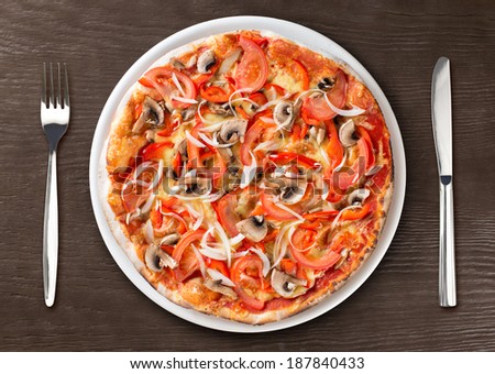 Italian pizza top view on plate with fork and knife