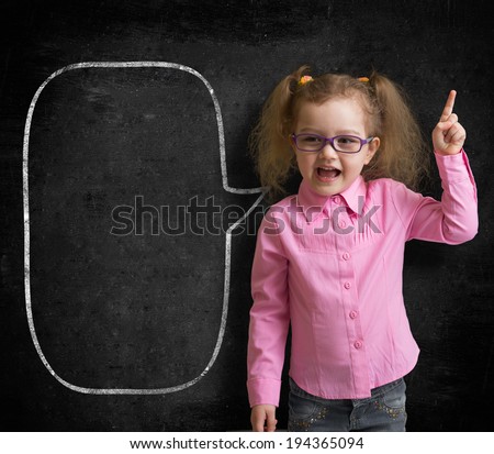 Funny child in eyeglasses standing near school chalkboard  as a teacher with blank speech bubble sketch.