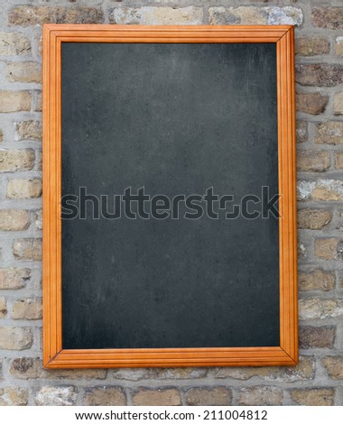 Aged blackboard hanging on brick wall as a background for your menu