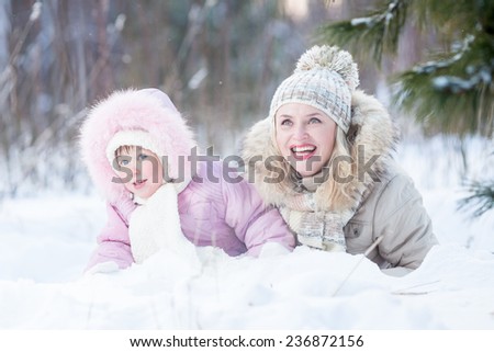 Happy family mother and daughter  playing with snow in winter outdoor