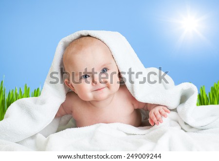 Cute smiling baby in towel on fresh air under sky and sun