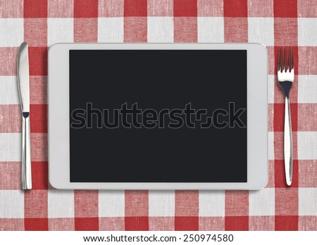 tablet pc looking like ipad, fork and knife on red checked tablecloth