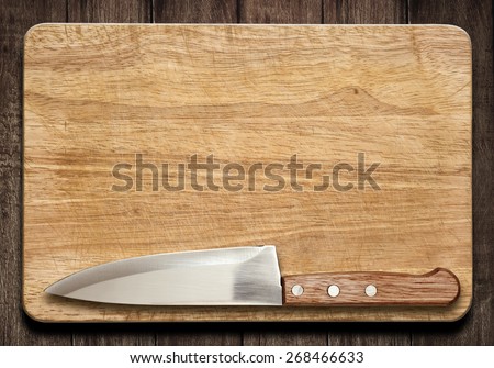Cutting board and knife on old wood table as a background