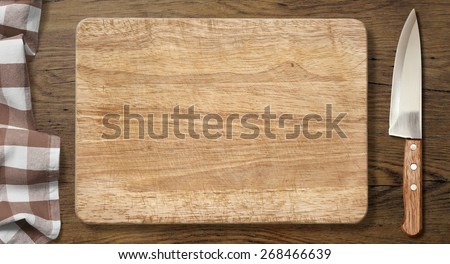 Cutting board and knife on old wood table with picnic tablecloth background