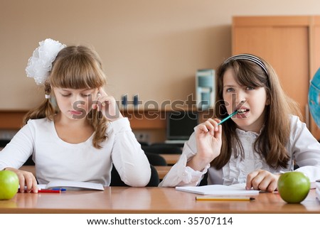 Two girls sitting at school desk during lesson