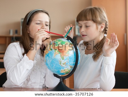Two schoolgirls search geographical location using globe