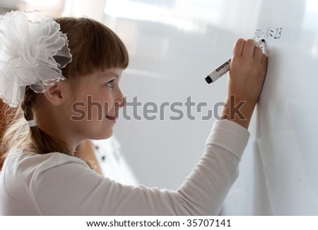 Schoolgirl is writing equation solution on whiteboard
