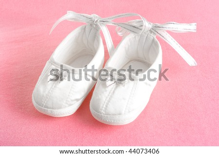 White baby\'s bootees on pink sheet