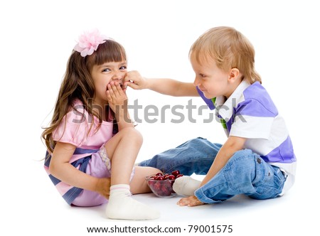 boy feeds little girl with cherry berries in studio isolated