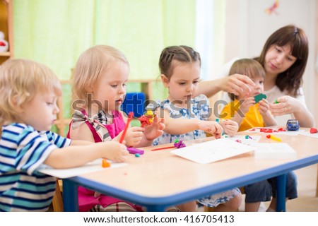 kids learning arts and crafts in kindergarten with teacher