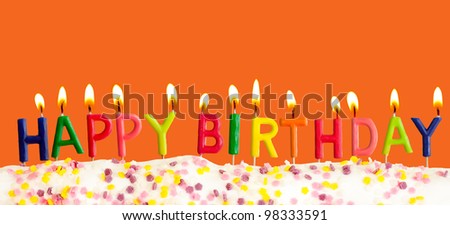 Happy birthday lit candles on orange background