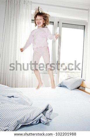 happy little girl jumping on her bed