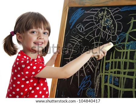happy little girl drawing picture with chalks on a black board