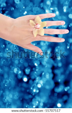 wellness - woman hand with orchid and blue bokeh