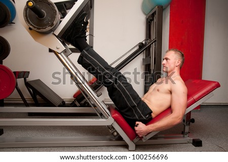 Man training leg muscles on a machine in fitness club