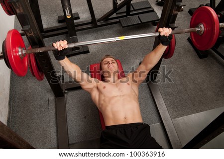 Man exercising his arm muscles by lifting two dumbell free weights in a fitness club.