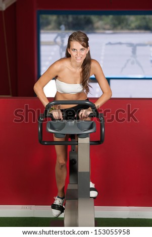 Beautiful active skinny woman riding a bike in fitness