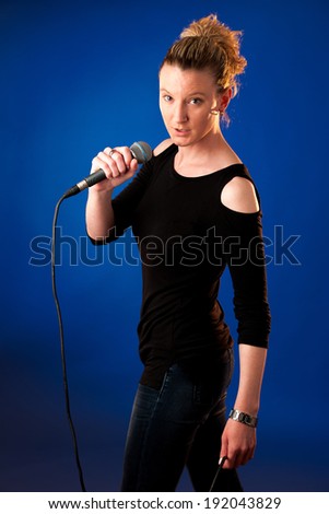 Woman singer on bluue background with microphone singing