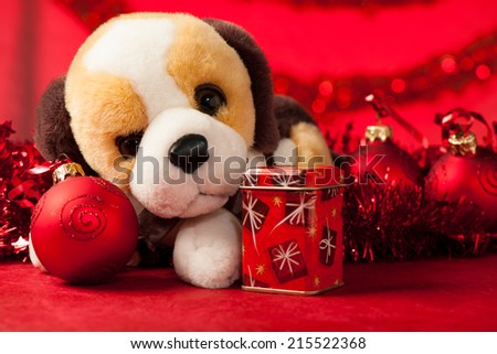 Toy dog with christmas ornaments over red
