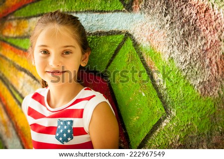 Young girl standing near graffiti wal on summer afternoon